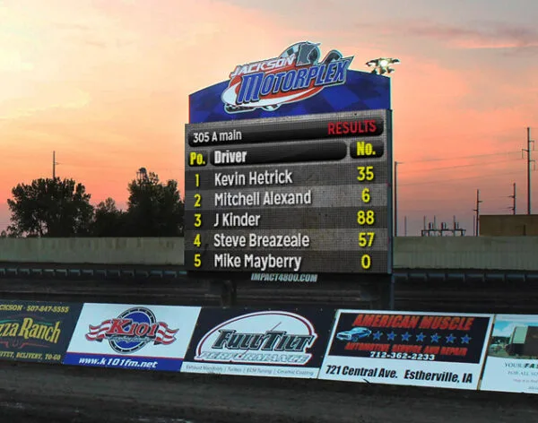 Jackson Motorplex LED display shows racing positions and driver names beneath the venue emblem beside the track grounds.