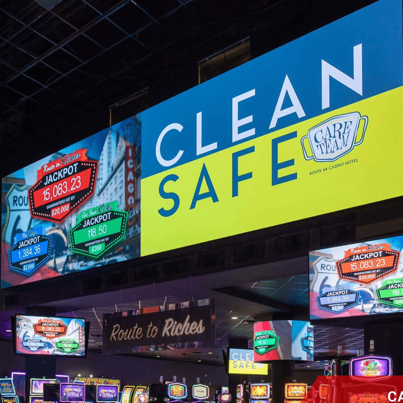 Large indoor LED display shows a bright Clean and Safe message above additional screens and gaming-area signage.