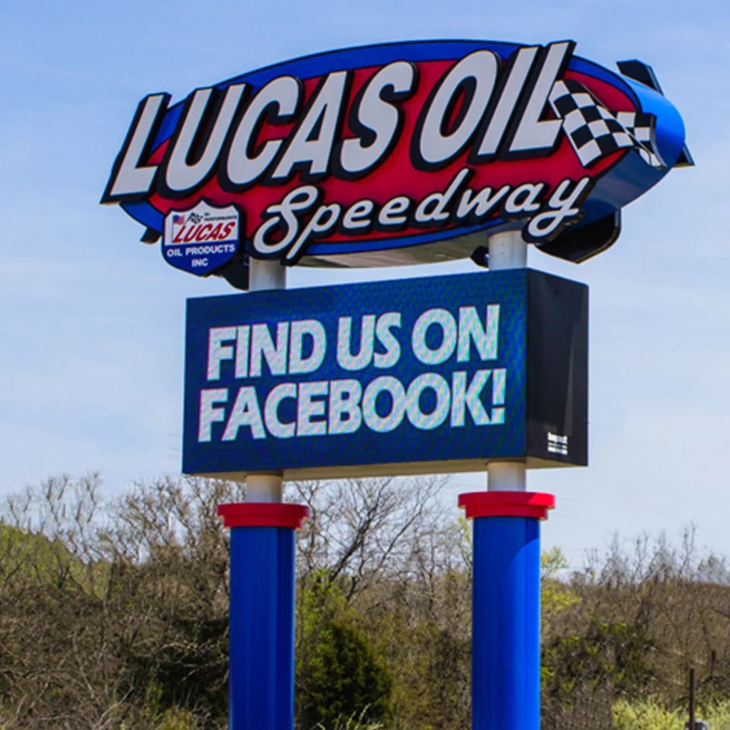 Lucas Oil Speedway roadside sign with checkered flag motif and high-brightness LED electronic message center says Find Us On Facebook.