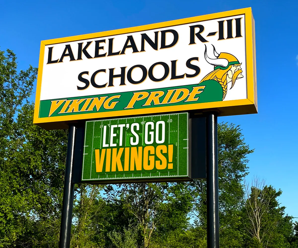 Lakeland R-III Schools monument sign with Viking mascot and raised text "VIKING PRIDE" is displayed above a solid-state, high-brightness LED electronic message center reading "LETS GO VIKINGS!" Background includes trees and clear blue sky.