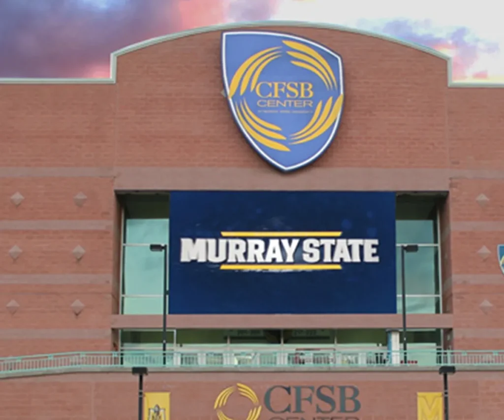 The CFSB Center's brick façade features a prominent Murray State solid-state LED electronic message center, with the university shield logo displayed above; an overcast sky forms the backdrop.
