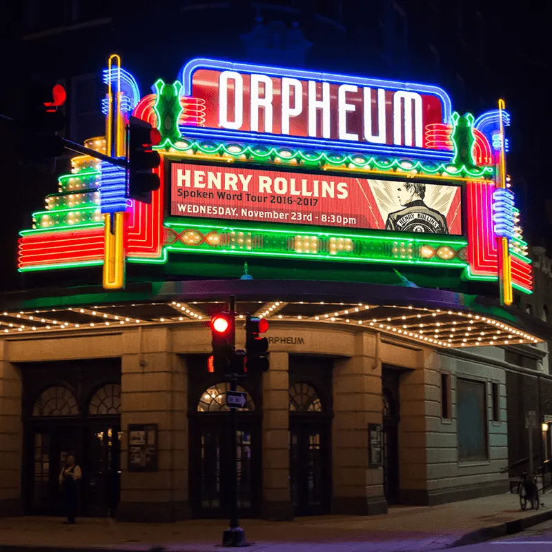 The Orpheum Theater features a high-brightness LED sign and electronic message center, constructed with an aluminum frame, displaying information for the Henry Rollins spoken word tour event in glowing neon at night.