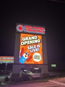 LED electronic message center for Red Apple Fireworks illuminated at night, showing “Grand Opening Sale is Live! Guaranteed lowest prices” text. The display features a cartoon eagle in a patriotic outfit and the address range 3610–3640 clearly visible at the bottom.