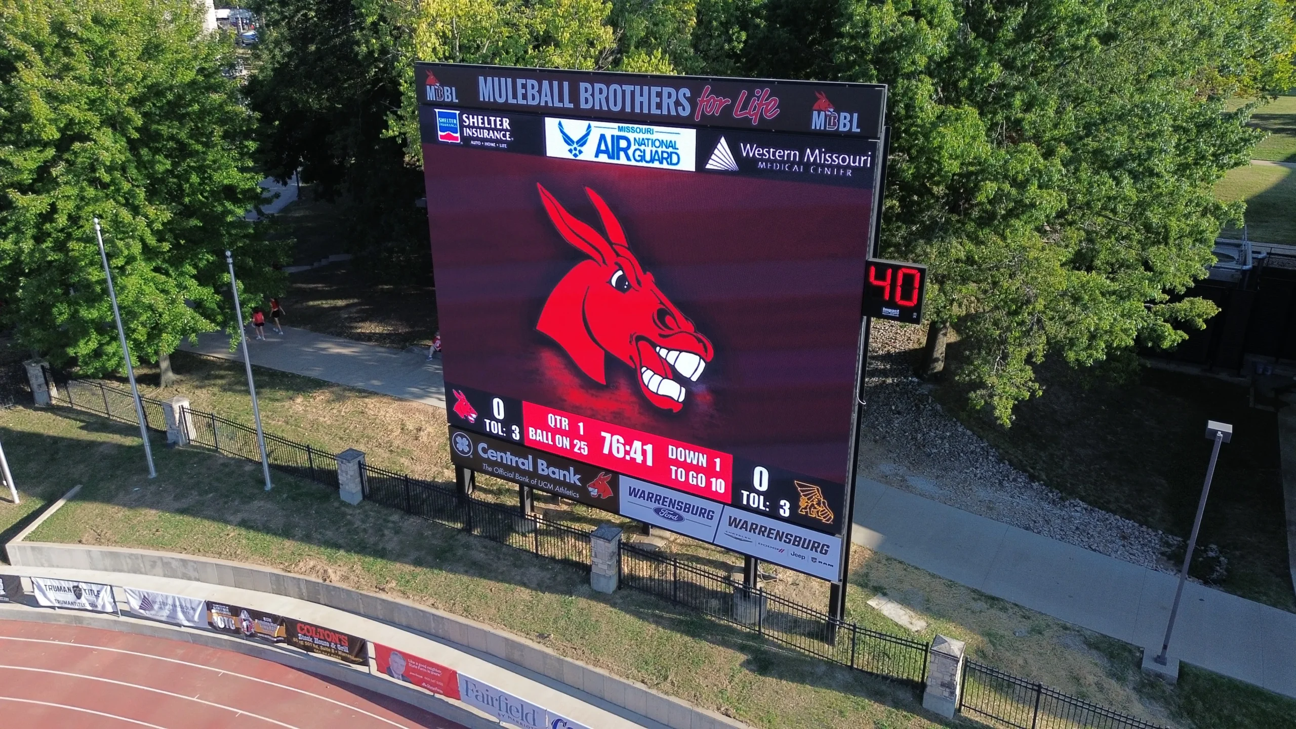 Elevated view of Walton Stadium’s scoreboard showing the red Mules mascot, game information, and sponsor panels.