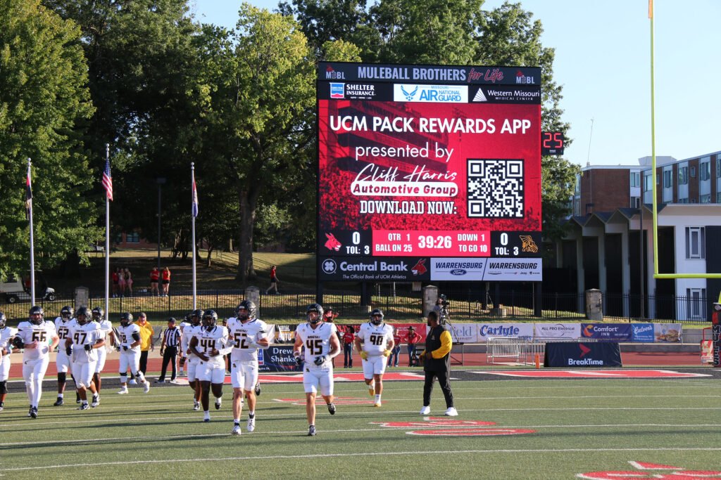 Walton Stadium scoreboard promoting a sponsor rewards app during a football game
