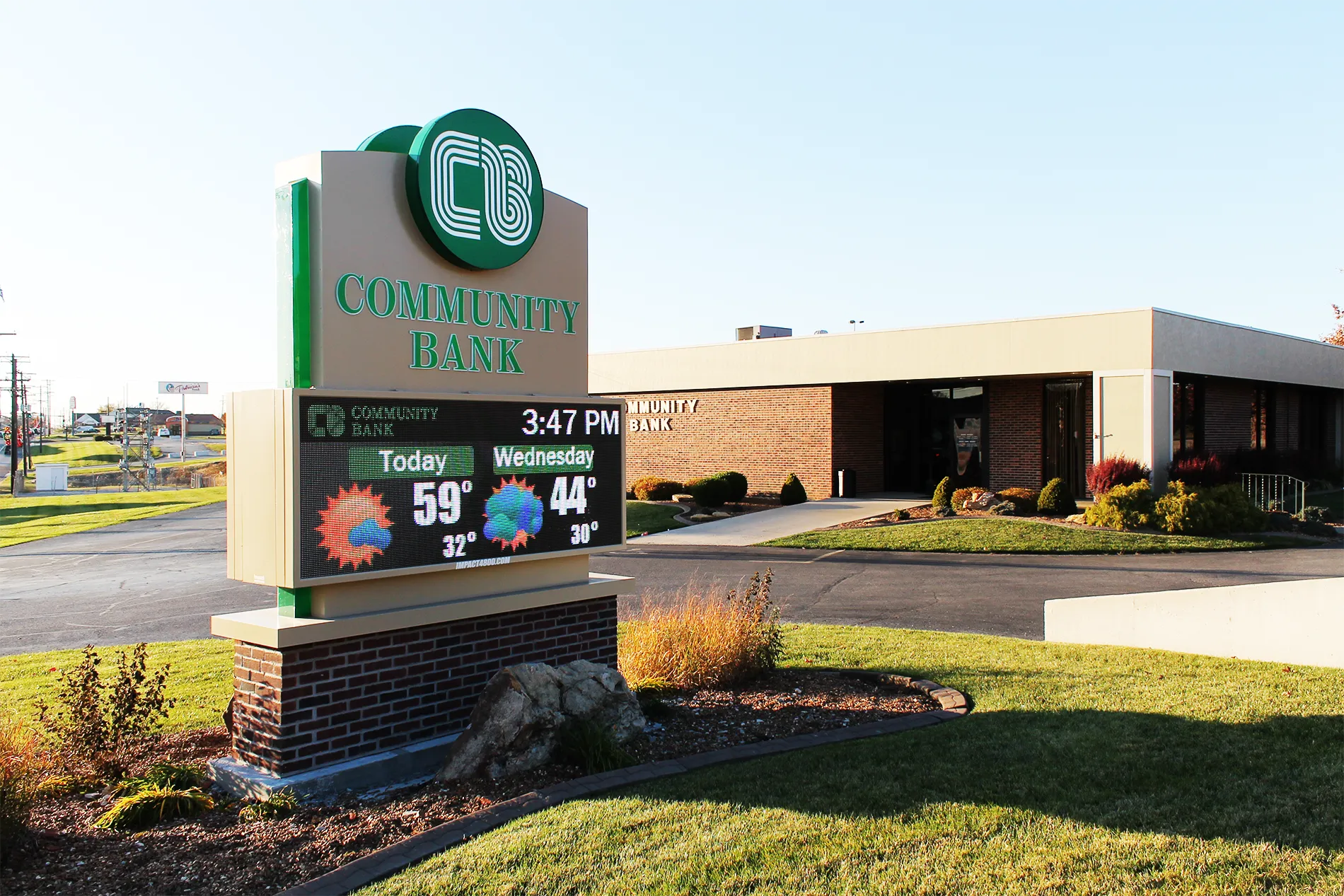 Community Bank of Marshall monument LED sign showing the time and a two-day weather forecast beside the bank building in Marshall, Missouri.