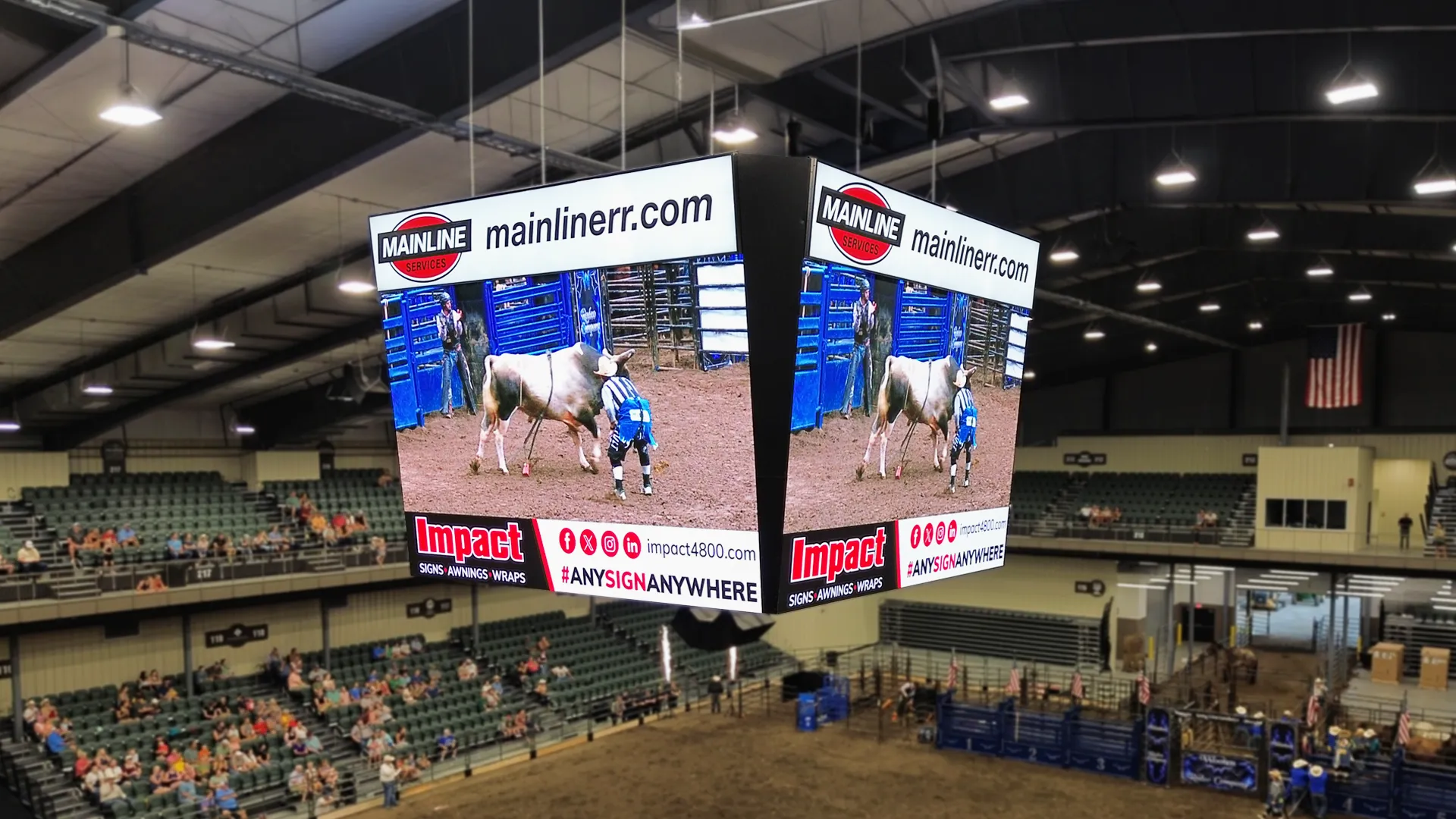 Suspended multi-sided STAX LED display showing rodeo footage and sponsor messages above the Missouri State Fairgrounds arena floor, surrounded by seating and roof beams.