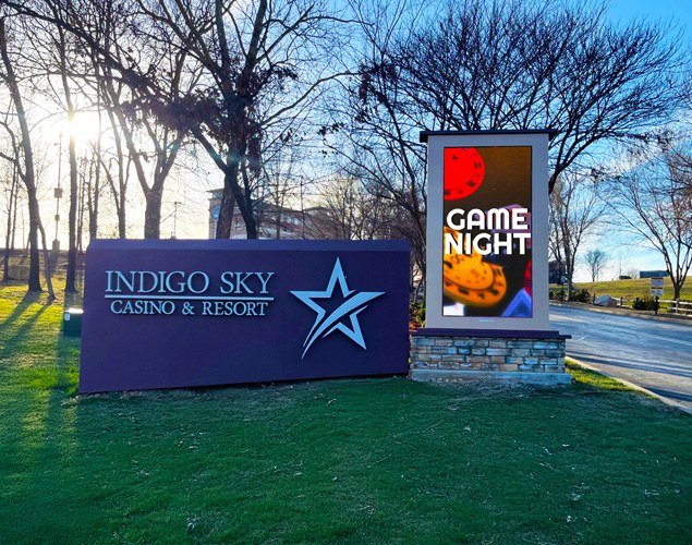 Indigo Sky Casino & Resort monument sign beside a vertical LED display promoting Game Night, with trees and a road in the background.