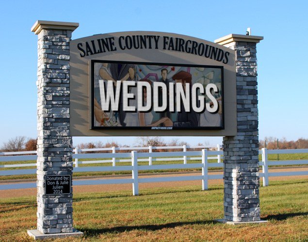 Saline County Fairgrounds LED sign displaying a weddings message between two stone-clad columns.